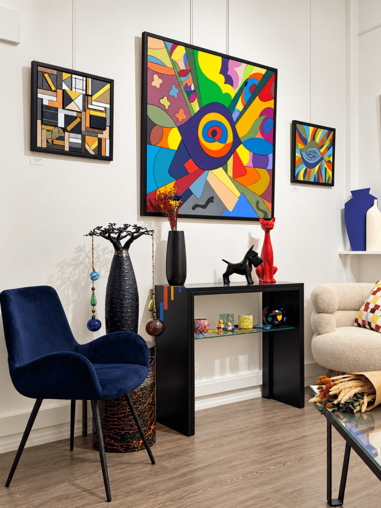 Atelier-galerie Couleurs en Design avec tableaux contemporains colorés, console noire, sculptures et fauteuils design.